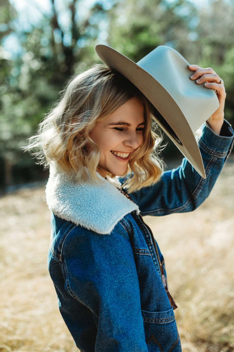 Hannah Marie smiling and tipping her hat, wearing a denim jacket